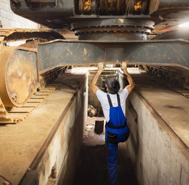 Technicien sous un engin de chantier de grande taille