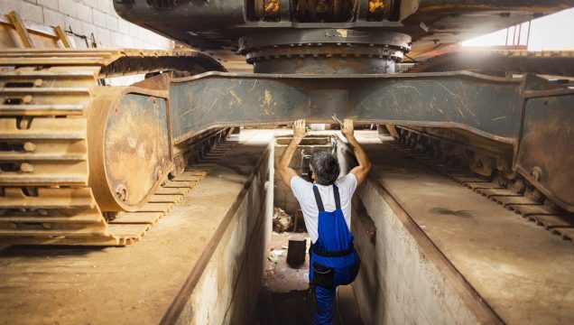 Technicien sous un engin de chantier de grande taille